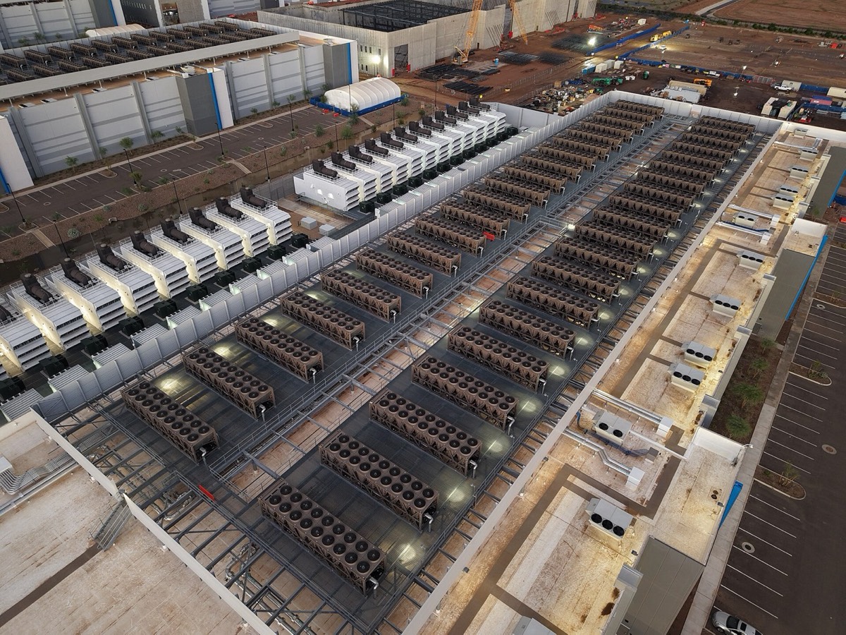 Data-center roof with long rows of cooling units and a line of backup generators beside the building