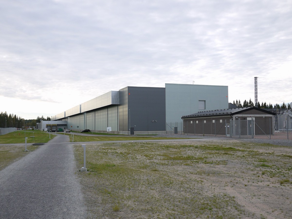 Long grey data-center building with a small electrical building in front, under an overcast sky in Luleå